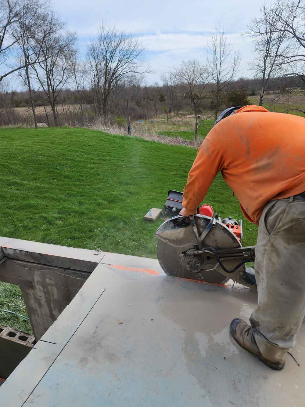 Man using a hand saw to cut concrete slab