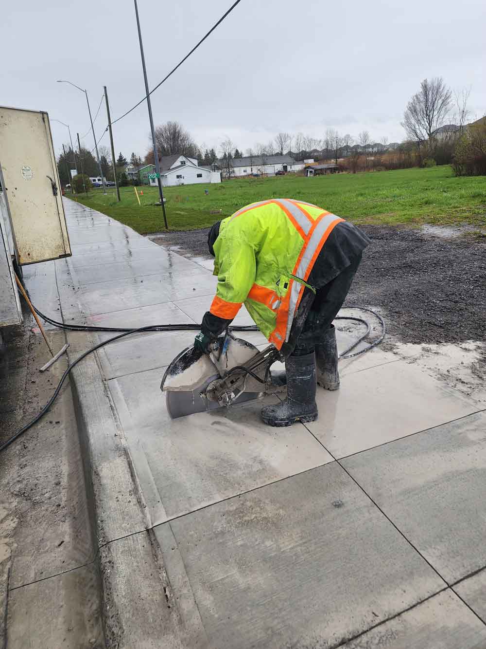 Man bent over using hydraulic hand saw to cut concrete