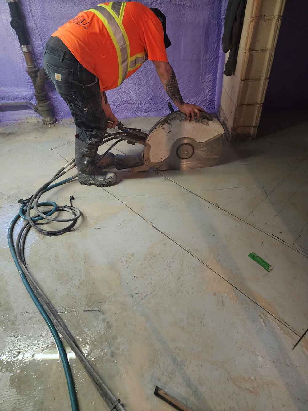 Man using hydraulic hand saw on floor of building under construction